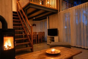 Ein gemütliches Wohnzimmer mit Kamin, einer Holztreppe und einem Fernseher.