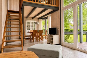 A wooden interior with a staircase, dining area, and a television. - Skandinavisches Ferienhaus mit Privatsauna im Hafendorf Müritz (Granzow)