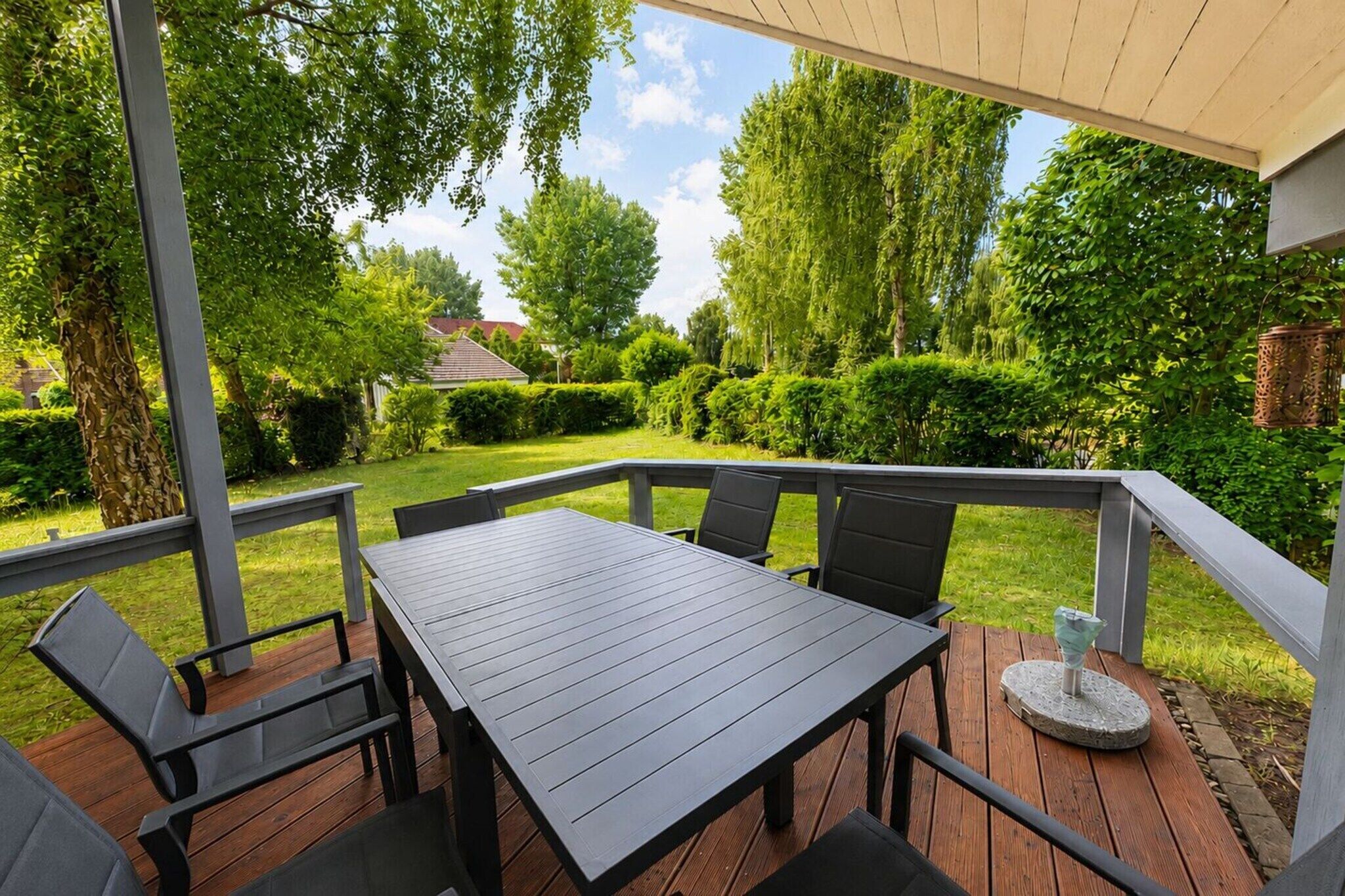 An outdoor patio with a table and chairs, surrounded by a wooden deck and a white railing.