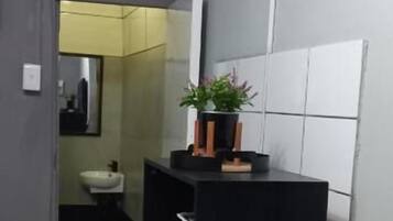 Ett kompakt hotellrum med en säng, ett litet skrivbord, en TV och en liten köksdel.