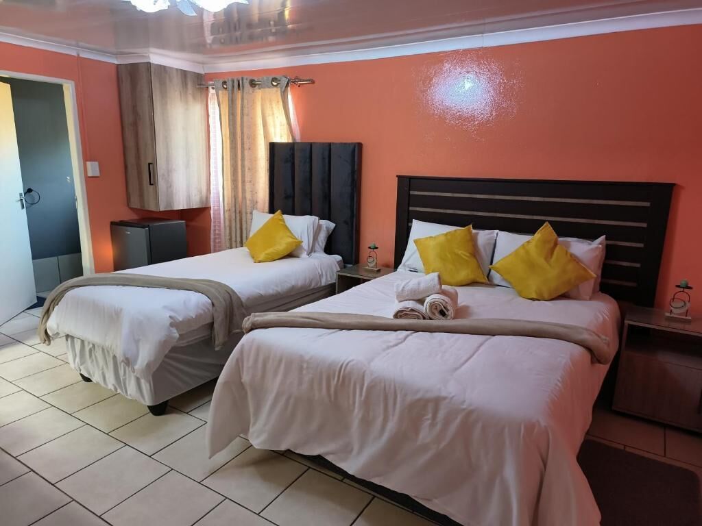Ein Hotelzimmer mit zwei Betten, jeweils mit weißer Bettwäsche und gelben Kissen, einem kleinen Tisch und einem Schrank.