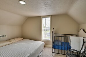 Ein Schlafzimmer mit einem Bett, einem Babybett, einem Fenster und einer Heizung.