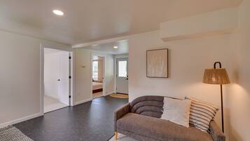 A modern living room with a sofa, a lamp, and a hallway leading to another room.