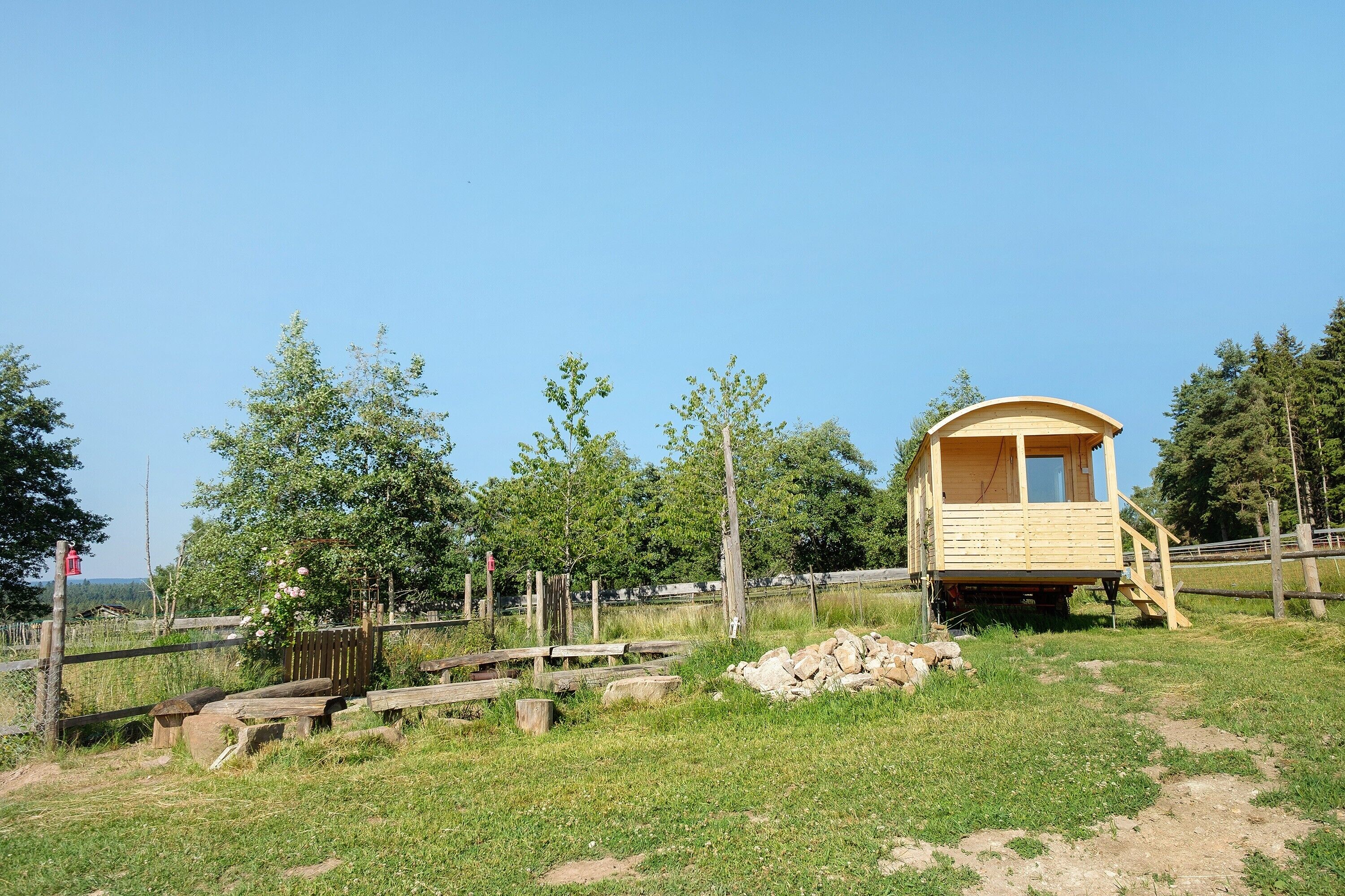 Eine Holzhütte mit Balkon, umgeben von einem Zaun und Bäumen.