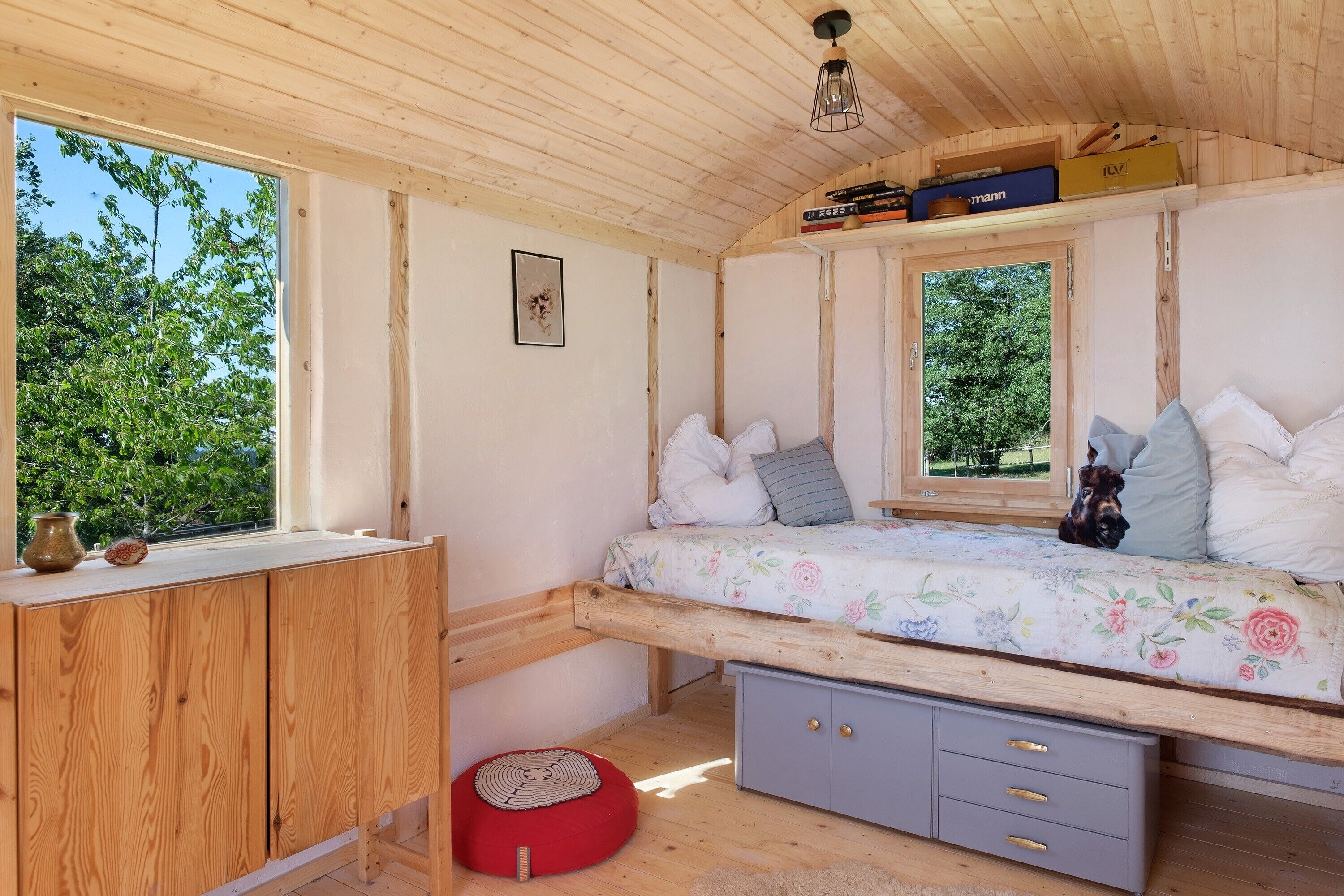 Ein Zimmer mit Holzboden, einem Bett, einem Schreibtisch und einem Fenster.