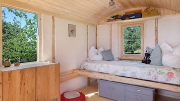 Ein Zimmer mit Holzboden, einem Bett, einem Schreibtisch und einem Fenster.