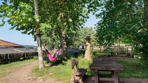 A rustic outdoor setting with a wooden bench, a hammock, and a picnic table. - Tiny Home “Bauwagen auf dem Falkenhof” – Nature Retreat with Shared Kitchen (Eisenbach)