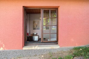A building entrance with a sliding glass door, a small outdoor seating area, and a painting on the wall.