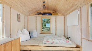 A small, cozy room with a bed, a window, and a shelf with books. - Tiny Home “Bauwagen auf dem Falkenhof” – Nature Retreat with Shared Kitchen (Eisenbach)