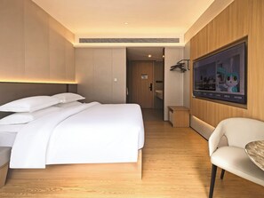 Een hotelkamer met een bed, een stoel, een televisie en een houten vloer.