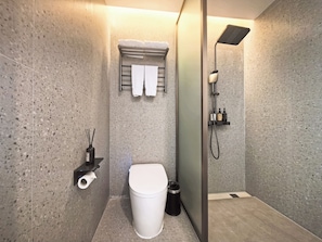 Een moderne badkamer met een douche, toilet en handdoekhouder.