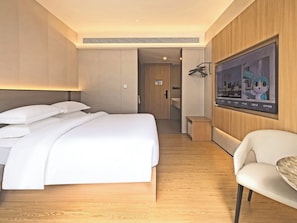 Een hotelkamer met een bed, zithoek en televisie.