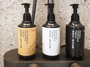 Tres recipients de productes de tocador amb dosificadors de bombona damunt un taulell.
