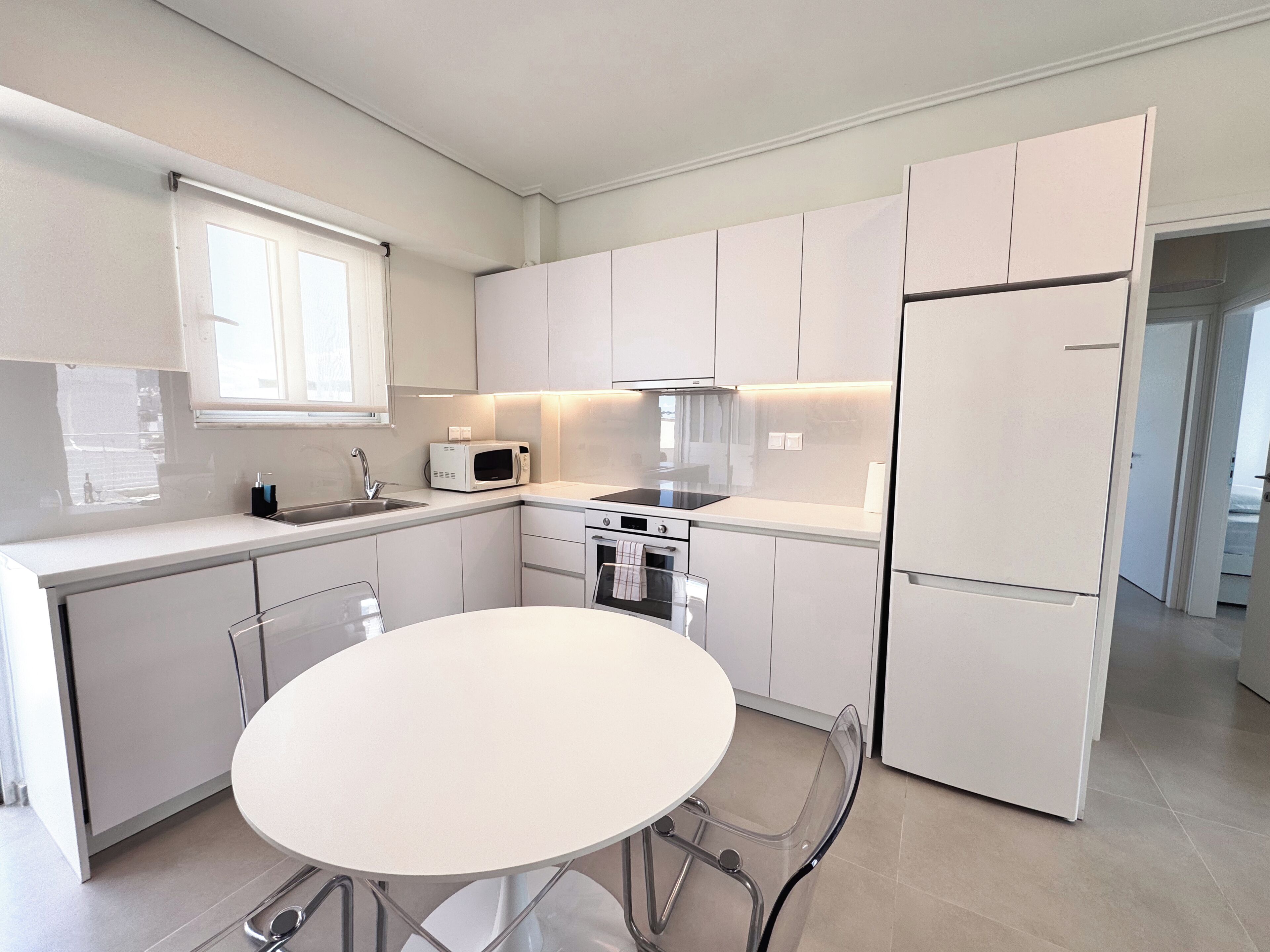 Una cocina moderna con alacenas blancas, un microondas, una estufa y un refrigerador.