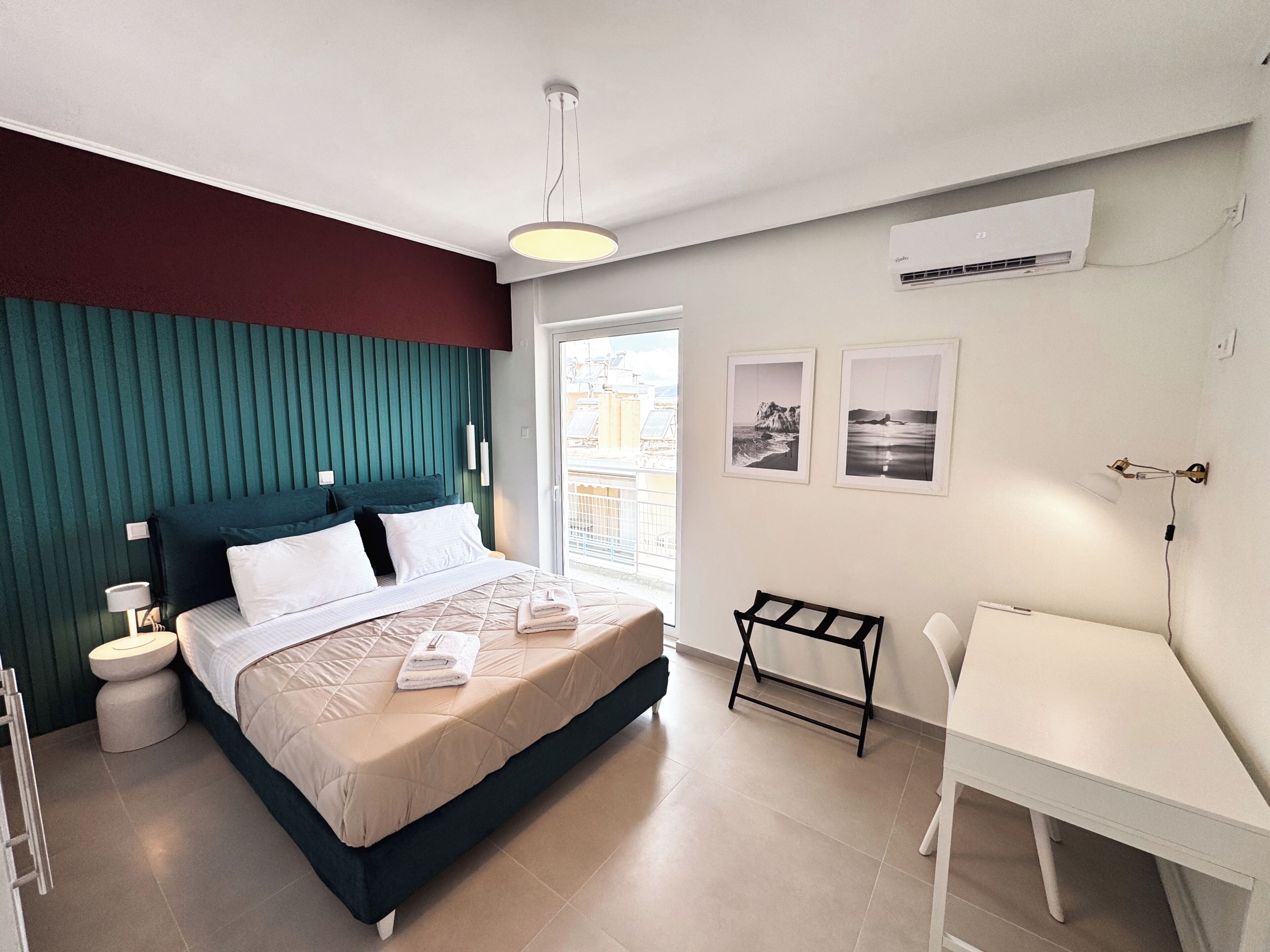 Un dormitorio moderno con cama, mesitas de noche, un escritorio y vistas al exterior.