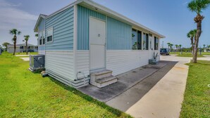 Ein Bungalow mit Veranda, einer kleinen Treppe und einer sichtbaren Klimaanlage.