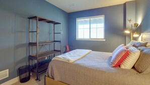 Een slaapkamer met een bed, een raam, een metalen rek en een stoel.
