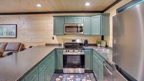 Una cocina con paredes de madera, un refrigerador de acero inoxidable, un microondas, un horno y un lavamanos.