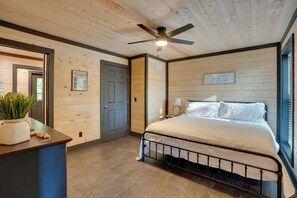 Ein Schlafzimmer mit einem Bett, einem Deckenventilator, einem Fenster und einer Tür.