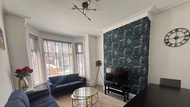 Una sala de estar con sofá, televisión y mesa de comedor.