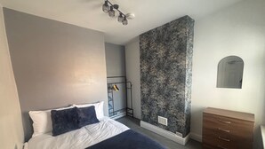Un dormitorio con cama, cómoda, armario y espejo en la pared.