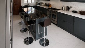 Una cucina moderna con isola centrale, sgabelli da bar, piano cottura e frigorifero.