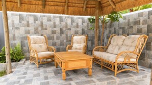 Una terrazza esterna con mobili in vimini e un muro di pietra a fare da sfondo.