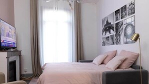 Una habitación de hotel moderna con cama, televisor, chimenea y una pared decorada con fotografías en blanco y negro.