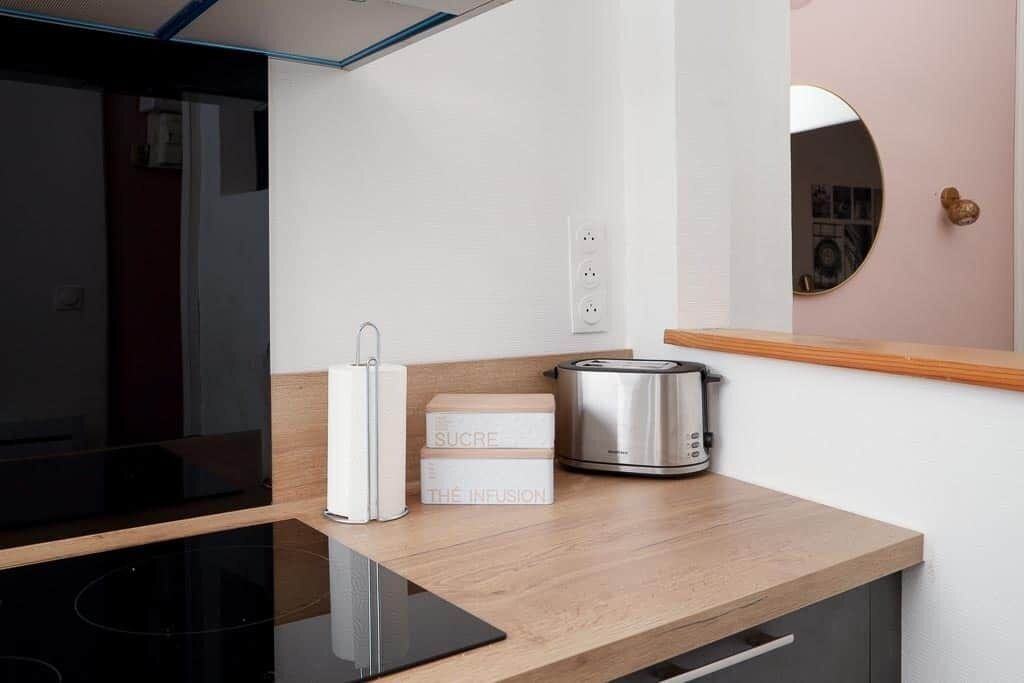 Een moderne keuken met een inbouwoven, een broodrooster en een doos met de tekst 'SUCRE THE INFUSION'.