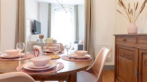 Un comedor con una mesa de madera dispuesta para cuatro personas, un aparador con adornos y vista a una sala de estar.