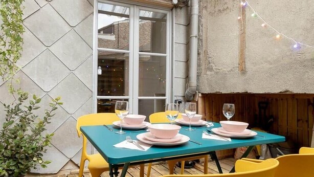 Comedor con una mesa preparada para cuatro, sillas amarillas y vajilla rosa.