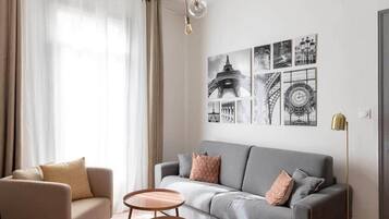 Een moderne woonkamer met een grijze bank, een beige fauteuil en een kleine ronde tafel.
