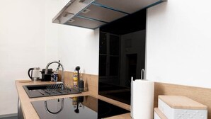 Una cocina moderna con encimera negra, pileta de acero inoxidable y ventana con vista.