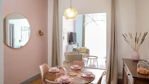 Un comedor con una mesa redonda dispuesta para cuatro personas, un espejo en la pared y una lámpara colgante.