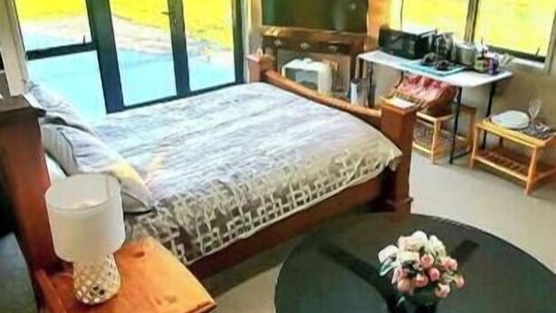 Une chambre à coucher avec un lit, une télévision, un bureau et une vue sur l’extérieur.