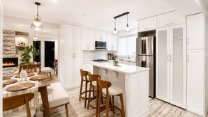 A modern kitchen with white cabinetry, a central island, bar stools, and pendant lighting.
