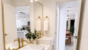 A bathroom with two sinks, a large mirror, and a toilet.