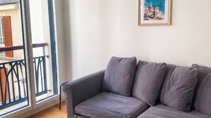 Un sofá gris, un reposapiés gris y un cuadro en una pared.