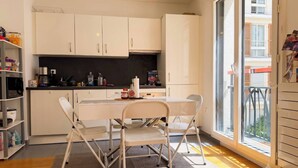 Una cocina moderna con armarios blancos, una mesa de comedor con sillas y vistas al exterior a través de un ventanal grande.