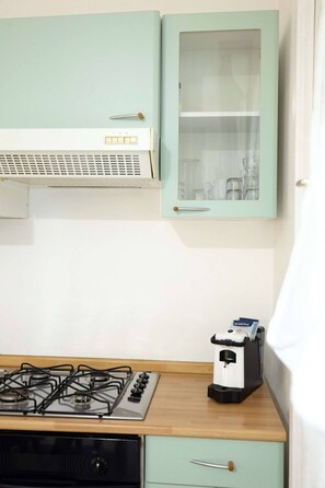 A kitchen with a gas stove, a microwave, and a cabinet with a glass door. - Charming Studio Apartment with Ocean View in Riccione (Riccione)