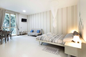 A bedroom with a bed, bedside table, lamp, and a desk with a chair. - Charming Studio Apartment with Ocean View in Riccione (Riccione)