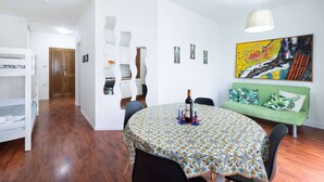 Een kamer met een ronde tafel, stapelbedden, een slaapbank en een schilderij aan de muur.