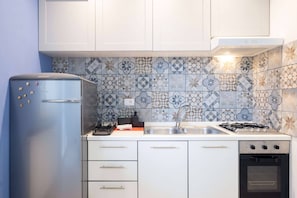 Eine Küche mit blauem Kühlschrank, einem Gasherd, einer Spüle und einem Einbauofen.