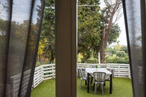 An outdoor patio with a white fence, a table with chairs, and a view of trees and greenery. - Charming Modern Loft with Sea View in Riccione Hills (Riccione)