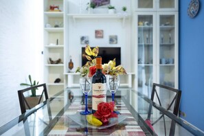 A dining table with a bottle of wine, glasses, and a red rose centerpiece. - Charming Modern Loft with Sea View in Riccione Hills (Riccione)