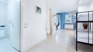 Hotellihuone, jossa on kerrossänky, kylpyhuone suihkulla sekä käytävä, joka johtaa toiseen huoneeseen.