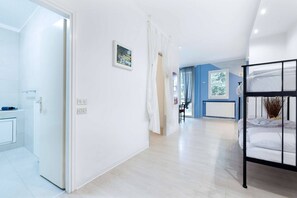 A hotel room with a bunk bed, a bathroom with a shower, and a hallway leading to another room. - Charming Modern Loft with Sea View in Riccione Hills (Riccione)