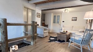 A rustic interior with a wooden floor, a white sofa, a chair, and a lamp. - Le Vosgien: Group Lodging (Saulxures-sur-Moselotte)