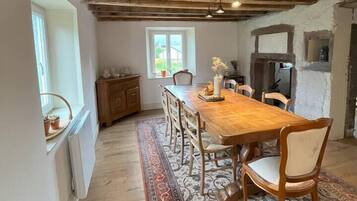 Un coin repas avec une table en bois, des chaises, un tapis et une cheminée.