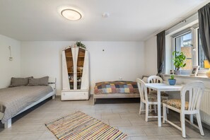 Habitació senzilla amb llit, taula petita amb cadires, un armari i finestra amb cortines.
